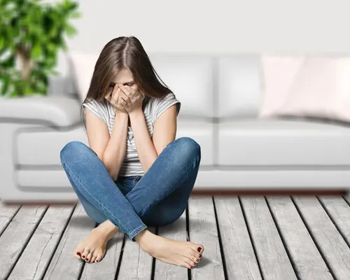 girl sitting on floor with hands covering her face